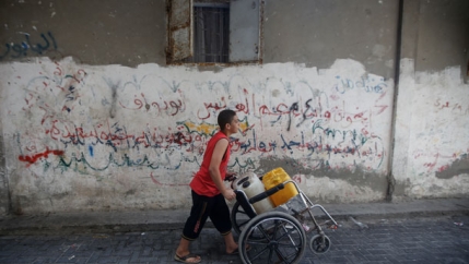 Gaza boy pushing wheelchair water
