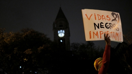 A demonstrator holds a sign reading 