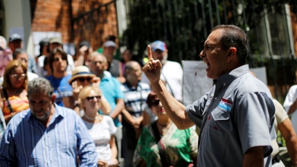 Lawmaker Richard Blanco is shown with his right hand rised and finger pointed up while giveing a speech.