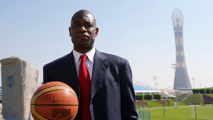 Congolese man in blue suit holds a basketball 
