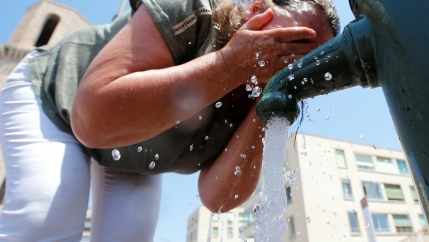 A woman cools off by splashing water on her face. 