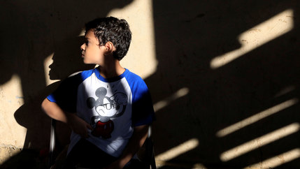 A young child is shown looking to his right and wearing a blue and white Mickey Mouse shirt.