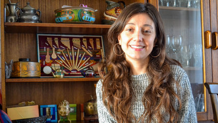 A woman with long hair and earrings smiles 