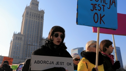 woman wearing sunglasses holds sign that says 
