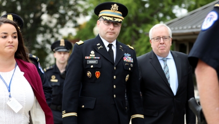 A man in a military uniform is walking with other people around him