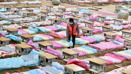 A worker amid a room of cots