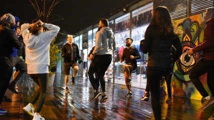People in athletic clothes warm up together on a sidewalk.