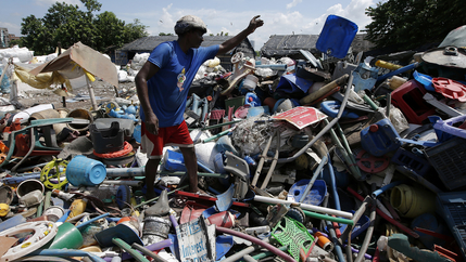 A man picks through a huge heap of plastic trash