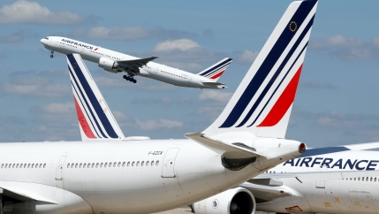 Three Air France white airplanes at the airport, one in the air