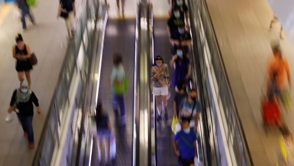 A woman wearing a protective face mask passes grocery shoppers amid the coronavirus disease (COVID-19) outbreak in Singapore on May 15, 2020.