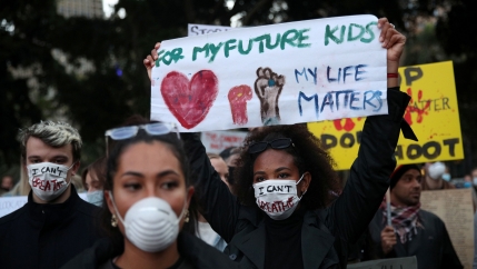 People protest, one woman with a sign 