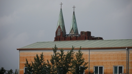 A church with two steeples with green tips in the distance 