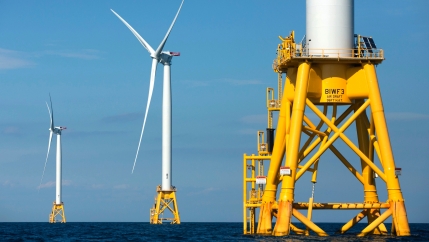 Three wind mills powered on yellow platforms in the ocean.