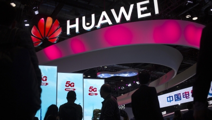 In this Oct. 31, 2019, file photo, attendees walk past a display for 5G services from Chinese technology firm Huawei at the PT Expo in Beijing.
