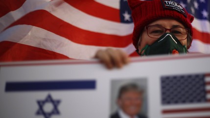 A supporter of US President Donald Trump waves Israeli and US national flags on the day of the U.S. presidential election, in Carmiel, northern Israel, Nov. 3, 2020.
