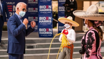 Joe Biden interacts with two Latinos wearing sombreros and Biden/Harris masks. 