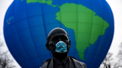 The bust of French statesman Robert Schuman, one of the founders of the European Union, is seen while environmental activists launch a hot air balloon during a demonstration outside of an EU summit in Brussels, Belgium, Dec. 10, 2020.