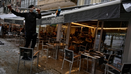 A worker wearing a face mask clears snow from the roof of a bar, in Pamplona, northern Spain, Dec. 5, 2020.