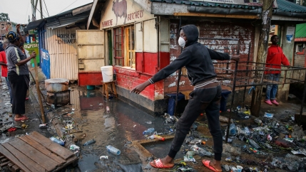 In this March 26, 2020, file photo, a boy wears a mask as a preventative measure against the spread of the coronavirus, as he navigates floodwaters mixed with garbage following heavy rains, in the Kibera area of Nairobi, Kenya.