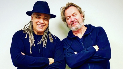 Two men wearing black sweaters pose for a photo.