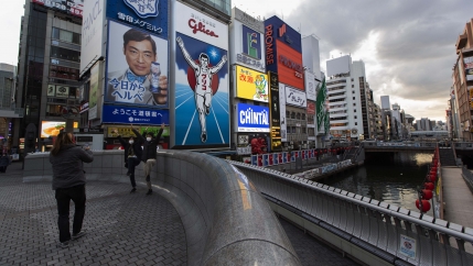 People pose for a photo, mimicking the character in an advertisement as they visit Ebisu-bashi bridge, a popular tourist spot in Osaka, western Japan, Nov. 30, 2020.