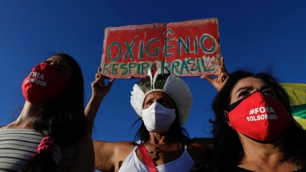 Demonstrators wearing masks with text written in Portuguese that read 