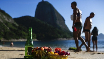 People stand next to offerings during a ceremony in honor of Yemanja, the goddess of the sea, which is part of New Year's celebrations to plea for relief from the coronavirus pandemic and asks for a better new year at Praia Vermelha beach in Rio de Janeir