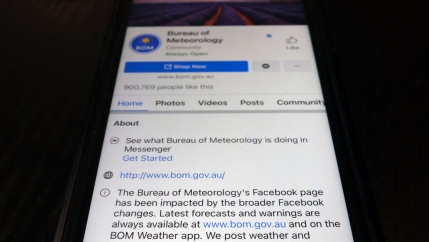 A close up photograph of a mobile phone showing the Bureau of Meteorology's page on the Facebook app.
