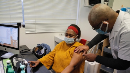 A doctor gives a patient the coronavirus vaccine in his office. 