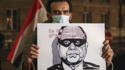 A man holds a placard depicting Egyptian President Abdul Fattah al-Sissi and reads he is a criminal as he stages a protest by the National Assembly in Paris, Dec. 8, 2020.