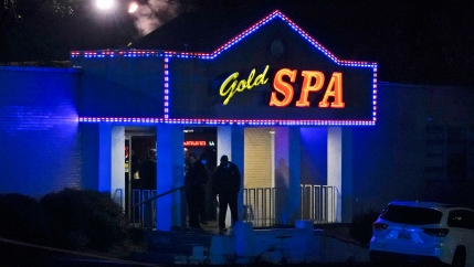 The front door of a spa is shown lit with blue colors and a sign above the entrance with the name, Gold Spa in neon lighting.