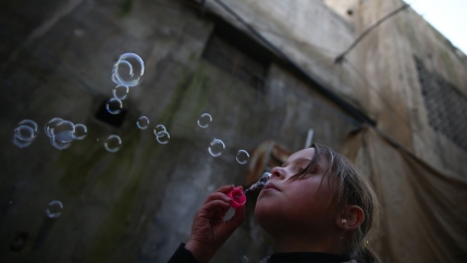 A young girl blows bubbles in the Douma neighborhood of Damascus, Syria, Jan. 19, 2017.