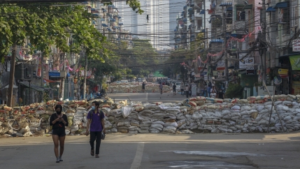 People walk along a deserted road blocked with improvised barricades build by anti-coup protesters to secure a neighborhood in Yangon, Myanmar, March 18, 2021.