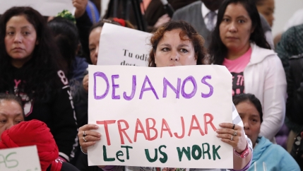 An attendee at the House Homeland Security Committee field hearing at Tougaloo College in Jackson, Mississippi, holds a sign written in English and Spanish, stating 