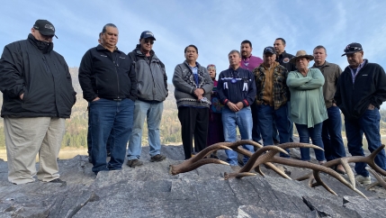 A group of Sinixt tribal members stand together near a mound and conduct a ceremony. 