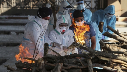 Family members of a person who died due to COVID-19 light the funeral pyre at a crematorium 