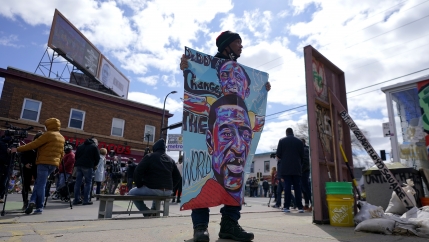 A man holds a sign at George Floyd Square, April 21, 2021, in Minneapolis, a day after former Minneapolis police Officer Derek Chauvin was convicted on all counts for the 2020 death of Floyd.