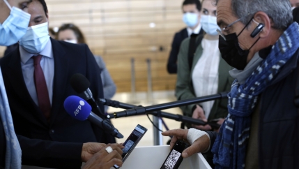 A passenger shows his PCR test result on his phone as he boards a plane at an airport