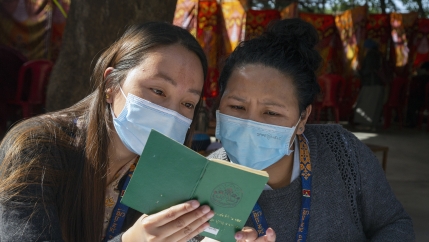 Exile Tibetan booth officials look at a green book, a necessary document for Tibetans to vote, during the second and final round of voting to elect their parliamentarians and the leader of the Central Tibetan Administration