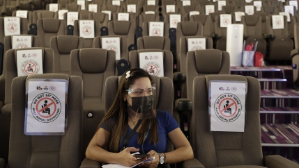 A sole woman waits in an empty movie theater-turned vaccination hub for her vaccine at a mall