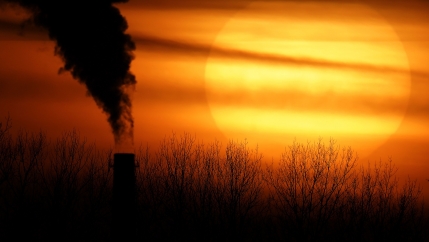 A setting sun near a smokestack. 