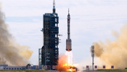 The long shaft of several staged rocket boosters are shown with jet fire streaming out of the exhaust.
