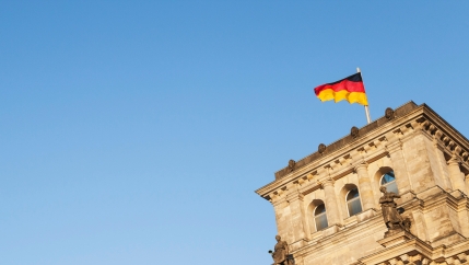 Black, red and yellow German flag waves on top of a building