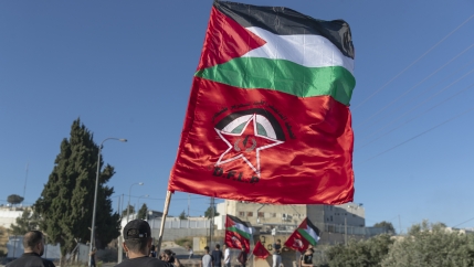 Palestinian protesters fly Palestinian flags and flags of the Democratic Front for the Liberation of Palestine, DFLP, during clashes with Israeli soldiers at the entrance the Jewish settlement of Beit El, background near the West Bank city of Ramallah.