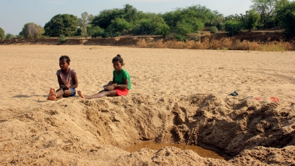 Children sit by a dug out water hole in a dry river bed in the remote village of Fenoarivo, Madagascar
