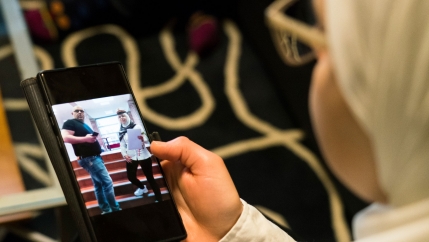 Faeza Satouf, from Syria, looks at a photo of her graduation day on her phone during an interview in Nivaa, Denmark, Wednesday, April 21, 2021. 