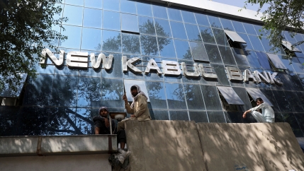 Afghans sit on the wall as people wait for hours to withdraw money, in front of Kabul Bank, in Kabul, Afghanistan, Sunday, Aug. 15, 2021. 
