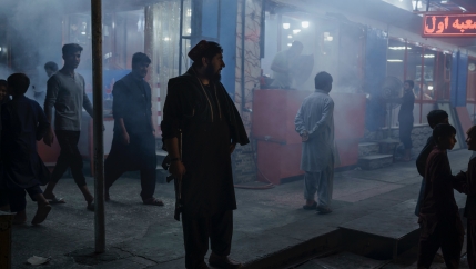 A Taliban fighter stands in the corner of a busy street at night in Kabul, Afghanistan, Sept. 17, 2021.