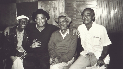 A black and white photo of Buena Vista Social Club members Ibrahim Ferrer, Eliades Ochoa, Comapy Segundo and Puntillita Licea.