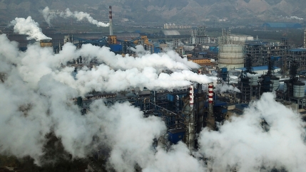 Several tall smoke stacks are shown with red and white stripes and large clouds of smoke pouring from them.
